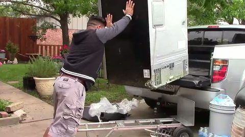 a man pushes a stainless steel refrigerator up onto a pickup truck bed by himself