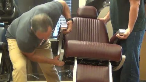 man removing the armrest of a barber chair