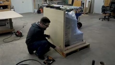 mover building a plywood crate around a palletized item, face visible